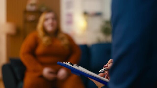 Silhouette of nervous young woman at therapy session, psychologist making notes
