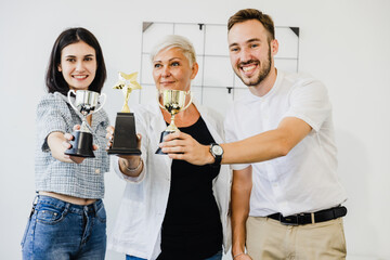 Cheerful group of businesspeople winning the cup with hands up