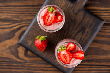 Tofu soy strawberry dessert in a glass on a wooden board. Vegan homemade. Lactose and sugar free. Top view.