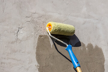 applying a primer to the wall with a yellow roller, showing the process of improving and repairing...