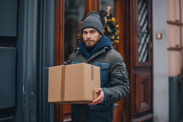 Delivery service. Courier. A courier holds parcels on the threshold near the door, close-up. Parcel delivery