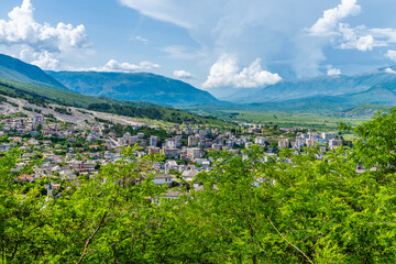 Obraz premium A view from the castle past trees towards the city of Gjirokaster, Albania in summertime