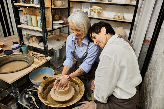 Two women work on pottery in an art studio.