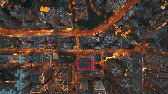 Aerial night view of Hong Kong street intersection, highlighting the dense urban traffic and contrasting building exteriors, illuminated by vibrant city lights