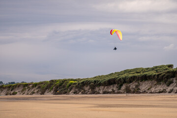 Success concept. A man paragliding in a clear sky on the coast of Ireland