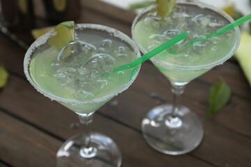Delicious Margarita cocktail in glasses on wooden table, closeup