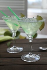 Delicious Margarita cocktail in glasses on wooden table