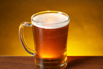 Mug with fresh beer on wooden table against dark background, closeup