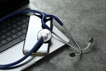 Modern electronic devices and stethoscope on grey table
