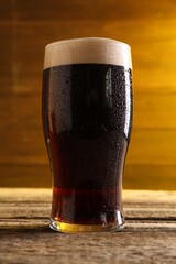 Glass of beer with froth on wooden table