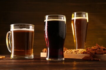 Glasses with different types of beer and snacks on wooden table