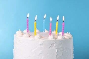 Tasty Birthday cake with burning candles against light blue background, closeup