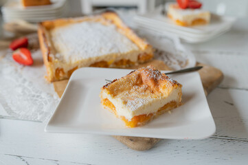 Slice of apricot cheesecake on a plate with whole cake in the background