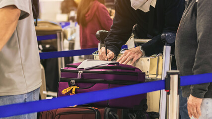 Hand of man traveler using pen filling immigration form at airport. Male tourist hand filling Immigration form on flight. Man passenger write immigration card. A man is writing, signing on a paper.