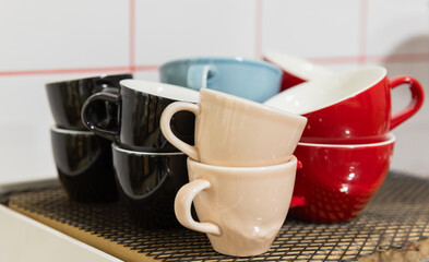 Set of bright ceramic cups stand in front of white wall