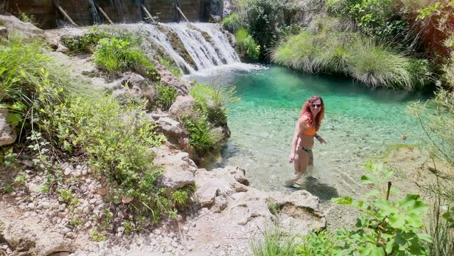 A woman is sitting in a natural clear pool of water