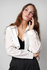 Confident Young Woman With Long Wavy Hair Posing in Casual Attire Against a Gray Backdrop