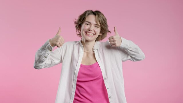 Positive woman with hand sign like, thumbs up gesture. Lady on pink background