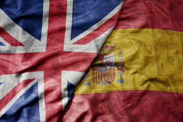big waving colorful flag of spain and national flag of great britain on the dollar money background. finance concept.