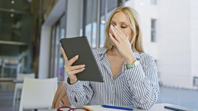 Blonde woman reading tablet with headache at office
