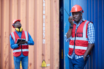 African factory worker or engineer using walkie talkie and talking about work in containers warehouse storage