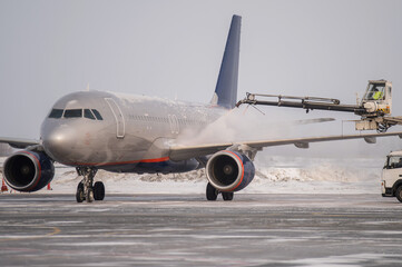 A technician sprays anti-icing coating on the wings of a passenger plane at the airport in winter. 