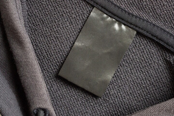 Blank black laundry care clothes label on black fabric texture background