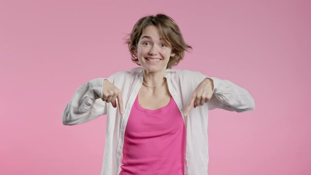 Blogger woman pointing down to advertising area. Pink background.Click subscribe