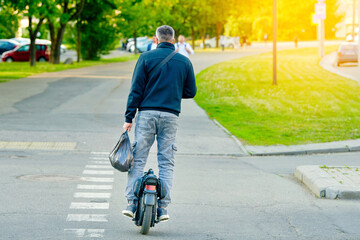 Man cycling on electric self balancing wheel, personal electrical transport. Man enjoying an outdoor adventure on an electric unicycle, modern transportation alternative in city setting © Tricky Shark