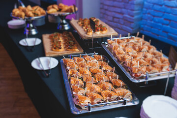 Beautifully decorated banquet catering table, with variety of with different food snacks appetizers on corporate birthday party event or wedding celebration, canape, salad, delicatessen setting