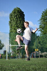 A young man in sportswear is playing soccer, training on a football pitch in the morning. Dedication and passion for the sport, the essence of morning exercise and practice outdoors © AlDa.videophoto