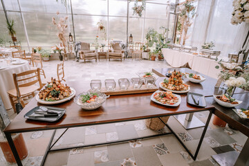 Valmiera, Latvia - September 9, 2023 - A wedding reception buffet table with various appetizers, salads, and glassware in a bright, elegant venue.