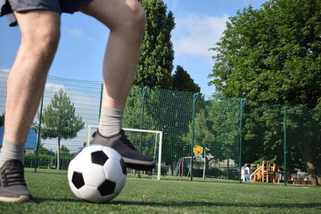 A young man in sportswear is playing soccer, training on a football pitch in the morning. Dedication and passion for the sport, the essence of morning exercise and practice outdoors