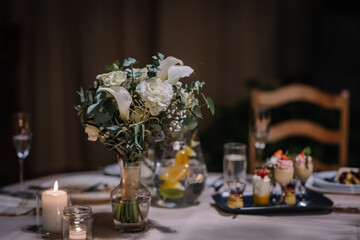 Valmiera, Latvia - September 9, 2023 - A beautifully set table with a floral centerpiece, candles, and a tray of desserts, creating an elegant and intimate dining atmosphere.