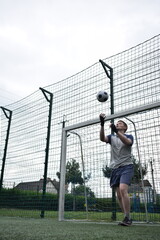 A young man in sportswear is playing soccer, training on a football pitch in the morning. Dedication and passion for the sport, the essence of morning exercise and practice outdoors