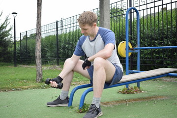 A young man in sportswear engages in a workout, using a sport tool for physical exercises on a...