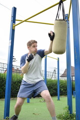 A dedicated young athlete boxing, puts in the hard work, training on gym equipment outdoors to...