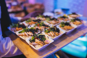 Beautifully decorated banquet catering table, with variety of with different food snacks appetizers on corporate birthday party event or wedding celebration, canape, salad, delicatessen setting