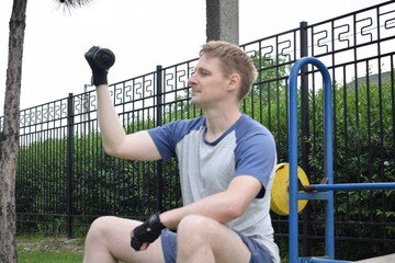A young man in sportswear engages in a workout, using a sport tool for physical exercises on a...