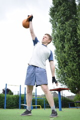 A young man in sportswear engages in a workout, using a sport tool for physical exercises on a...