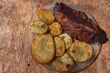 plate of roast beef with rustic potatoes with oregano on rustic wood table