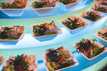 Beautifully decorated banquet catering table, with variety of with different food snacks appetizers on corporate birthday party event or wedding celebration, canape, salad, delicatessen setting