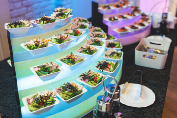 Beautifully decorated banquet catering table, with variety of with different food snacks appetizers on corporate birthday party event or wedding celebration, canape, salad, delicatessen setting