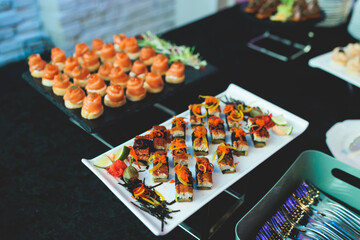 Beautifully decorated banquet catering table, with variety of with different food snacks appetizers on corporate birthday party event or wedding celebration, canape, salad, delicatessen setting