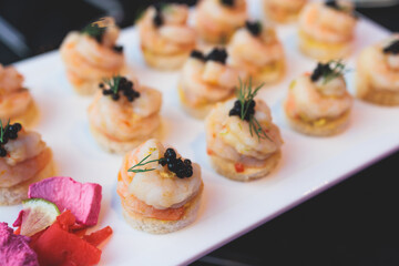 Beautifully decorated banquet catering table, with variety of with different food snacks appetizers on corporate birthday party event or wedding celebration, canape, salad, delicatessen setting