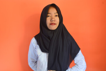 A Muslim Asian woman wearing a white shirt and black hijab is standing with a confident digital gesture giving coaching