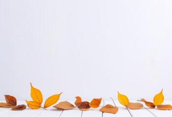 A flat lay of dried leaves on a white wooden table with a white wall in the background