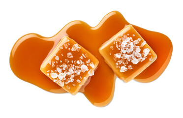 Two salty or salted caramel candy cubes topped with caramel sauce and sea salt on white background
