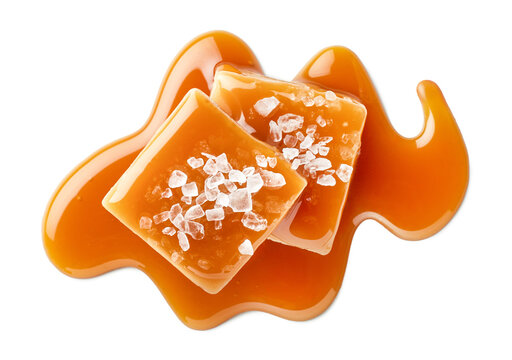 Two salty or salted caramel candy cubes topped with caramel sauce and sea salt on white background