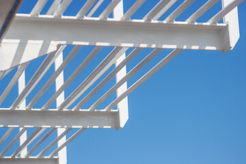 white painted iron girders and bracing bars against a clear blue sky